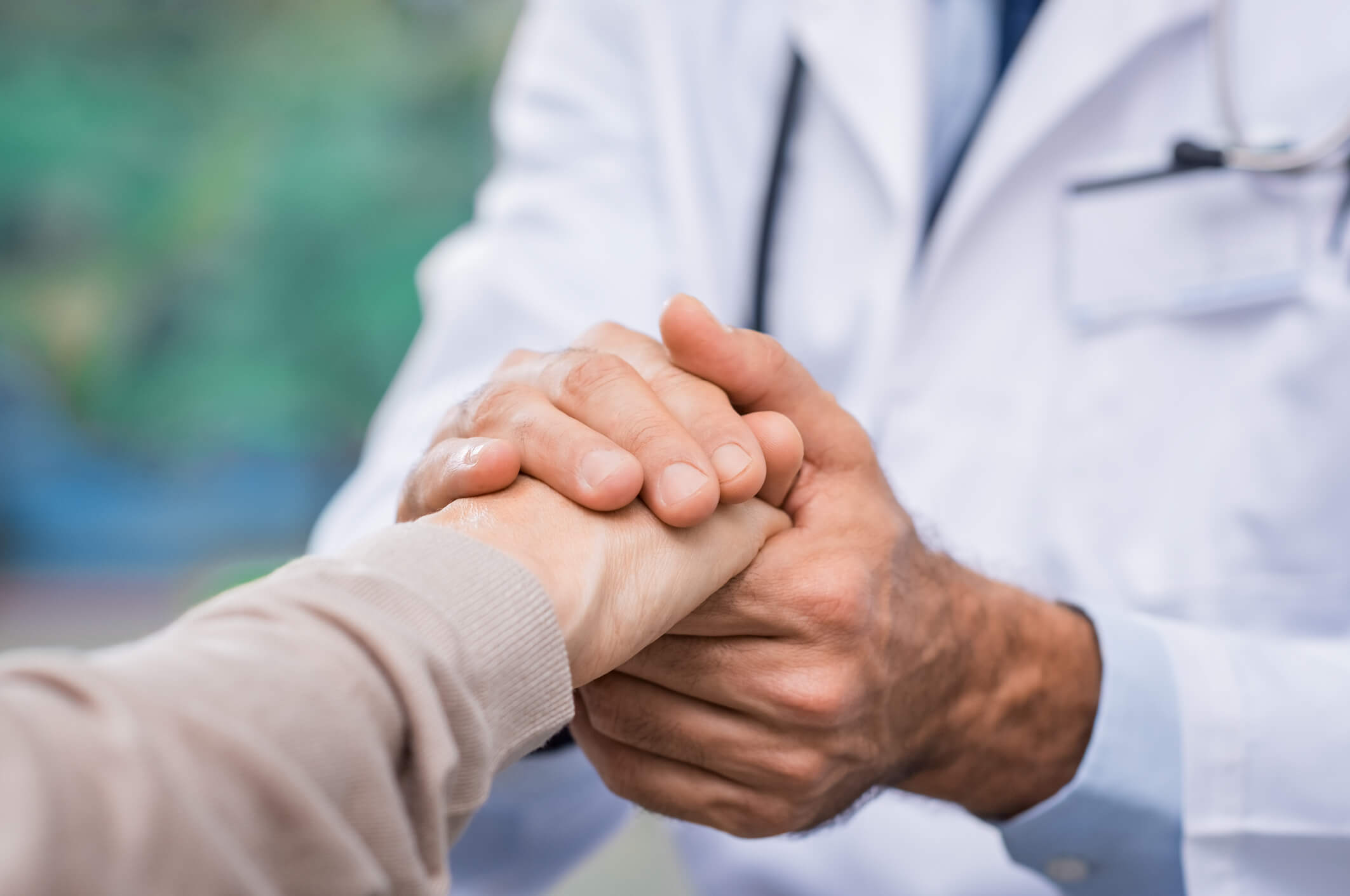 Close up of doctor hand reassuring her female patient at hospital. Closeup hands of medical doctor carefully holding patient's hands. Kind doctor giving real support for patient.